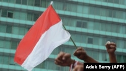 Bendera Indonesia dan kepalan tangan rakyat Indonesia yang menyerukan persatuan di Jakarta pada 4 Desember 2016. (Foto: AFP/Adek Berry)
