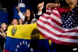 Members of the audience wave Venezuelan and American flags as President Donald Trump speaks to a Venezuelan American community at Florida Ocean Bank Convocation Center at Florida International University in Miami, Feb. 18, 2019.