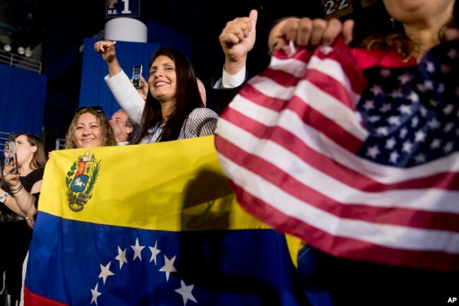 Members of the audience wave Venezuelan and American flags as President Donald Trump speaks to a Venezuelan American community at Florida Ocean Bank Convocation Center at Florida International University in Miami, Feb. 18, 2019.