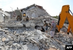 Members of the Syrian Civil Defense (White Helmets) search for victims amidst the rubble of a building that collapsed during reported airstrikes by pro-regime forces in the village of Beinin in the northern Idlib province, Aug. 20, 2019.