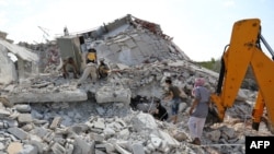 Members of the Syrian Civil Defense (White Helmets) search for victims amidst the rubble of a building that collapsed during reported airstrikes by pro-regime forces in the village of Beinin in the northern Idlib province, Aug. 20, 2019. 