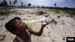 Seorang anak yang selamat dari tsunami sedang minum air dalam kemasan di daerah yang terkena tsunami.