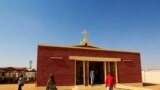 FILE - South Sudanese living in the North walk near a Catholic church during Christmas Day celebrations in the Umbada locality of Omdurman, Dec. 25, 2013. 