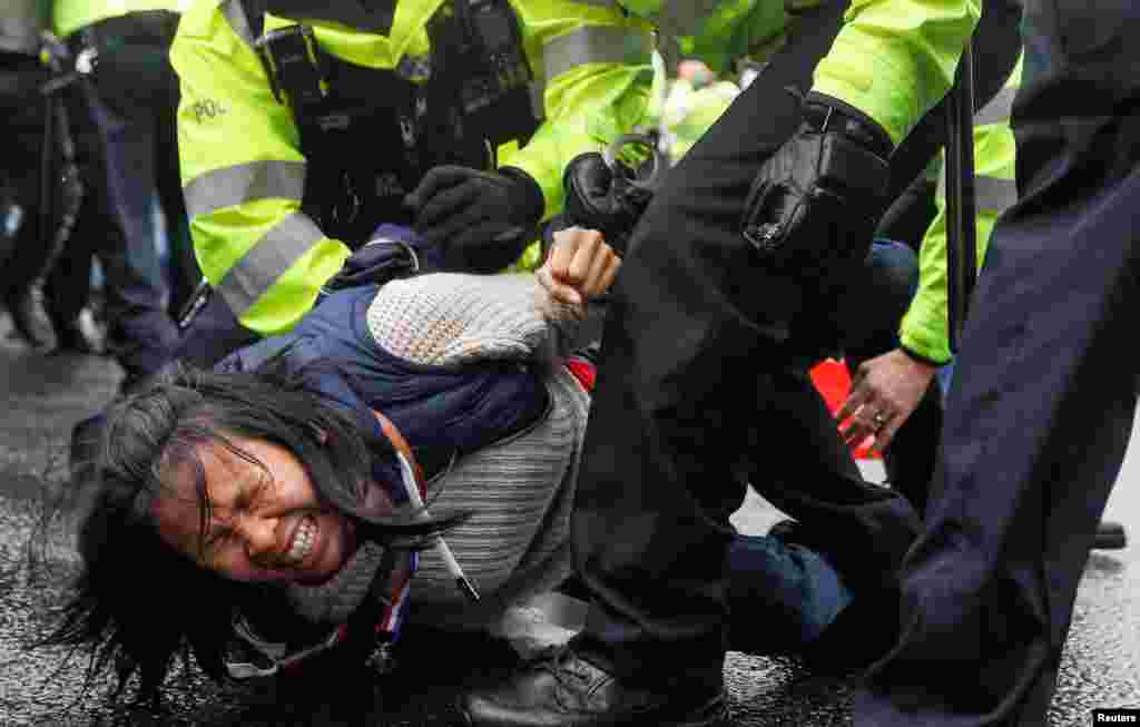 An anti-vaccine demonstrator is detained by police officers during a protest in Westminster, Britain.