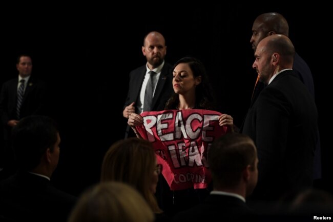 A protester holding a sign that says "Peace with Iran" is escorted out of the room during U.S. Secretary of State Mike Pompeo's remarks during the United Against Nuclear Iran Summit on the sidelines of the U.N. General Assembly in New York, Sept. 25, 2018.