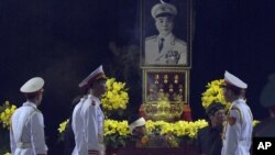 Vo Dien Bien (nomor dua dari kanan, berpakaian hitam), anak laki-laki Jenderal Vo Nguyen Giap dan pasukan kehormatan berdiri di dekat peti jenazah Giap di Tempat Persemayaman Nasional di Hanoi, Vietnam (12/10).