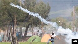 Un migrant renvoie une canette de gaz lacrymogène vers la police macédonienne lors d'une manifestation près du poste-frontière grec d'Idomeni, le 10 avril 2016.