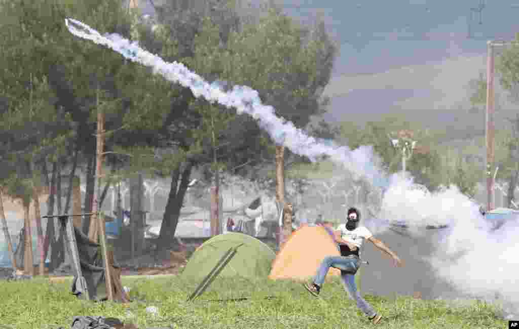 A migrant man throws a can of the tear gas back toward Macedonian police during a protest at the northern Greek border point of Idomeni, Greece.