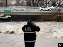 A Sparks firefighter takes a picture of the rising Truckee River, Sunday, Jan. 8, 2017, where it runs near the Grand Sierra hotel-casino along a line that divides the cities of Reno and Sparks, Nevada.