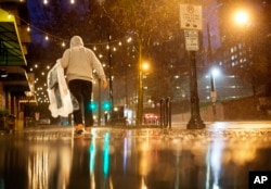 FILE - A person carries his dry cleaning while walking in the rain through midtown Atlanta, Wednesday, Dec. 23, 2015.