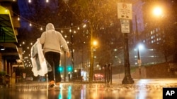 一名行人带着干洗的衣服冒雨走在亚特兰大市中城的街头。（2015年12月23日）