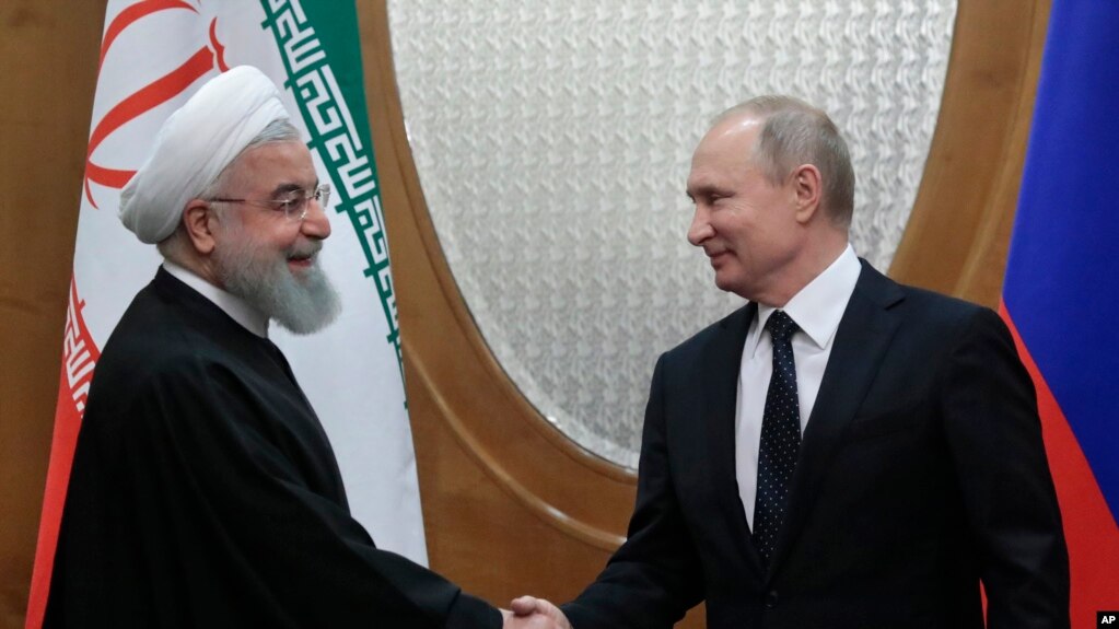 DOSSIER - Le président russe Vladimir Poutine (à droite) et le président iranien Hassan Rouhani se serrent la main avant les négociations dans la résidence de Bocharov Ruchei dans la station balnéaire de Sochi au bord de la mer Noire, le 14 février 2019.