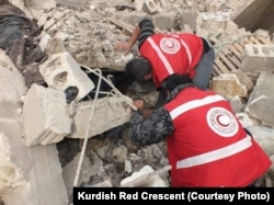 FILE - Kurdish Red Crescent workers search for survivors after an attack in Afrin, January 2018.