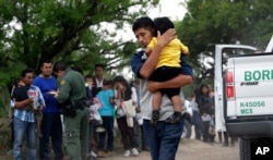 FILE - Jose Fermin Gonzalez Cruz holds his son, William Josue Gonzales Garcia, 2, as they wait with other families who crossed the border near McAllen, Texas, for Border Patrol agents to check names and documents, March 14, 2019.