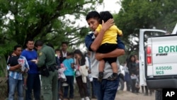 Des migrants d’Amérique latine ayant traversé la frontière près de McAllen (Texas) se dirigent vers des agents de la police des frontiers pour vérifier leurs documents, le 14 mars 2019.