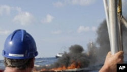 A cleanup worker watches a controlled burn near the Deepwater Horizon oil spill site.