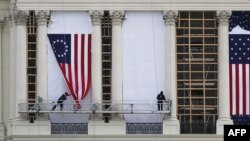 WASHINGTON, DC - JANUARY 13: Workers hang an early version of the American flag on the U.S. Capitol to be used as part of the backdrop to the presidential inauguration for President elect Donald Trump as he prepares to take the reins of power next week on January 13, 2017 in Washington, DC. The inauguration will take place on January 20th when President Barack Obama ends his 8 year run as Americas president. Joe Raedle/Getty Images/AFP