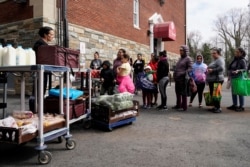 A member of staff gives food to families at the DC Bilingual School after the school was closed due to the global coronavirus pandemic in Washington, March 17, 2020.