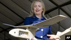 En esta foto la secretaria de Estado de EE.UU., Hillary Clinton, sostiene un drone usado en Uganda para encontrar y destruir explosivos que matan a soldados.
