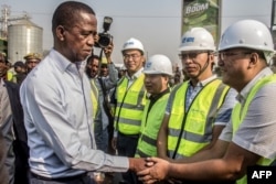 FILE - Zambian President Edgar Lungu, left, greets Chinese workers during a walk on a major road in Lusaka, Zambia, Sept. 15, 2018.