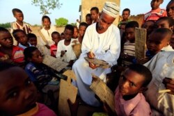 Syekh menuliskan ayat Al-Qur'an untuk dibaca murid-muridnya di kelas baca Al-Qur'an di Khalwa Syekh Tigani, Tulus, selatan Darfur, Sudan, saaat Ramadan, 6 Juni 2017. (REUTERS/Mohamed Nureldin Abdallah)