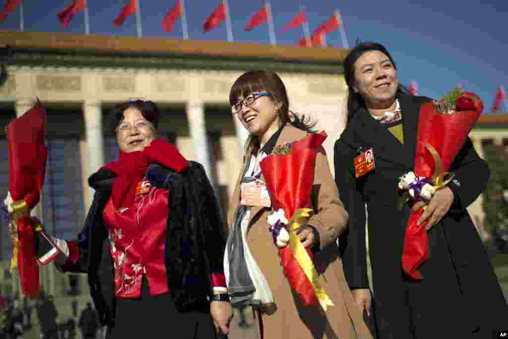 2018年3月8日国际妇女节，参加北京人民大会堂举行的全国政协全体会议的女代表拿着花束。