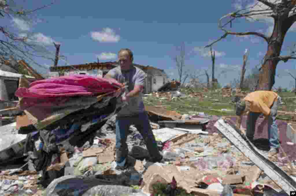 Mark Plunkett, left, with the help of Allen Southerland, right, find some of his wife's clothing in the debris of his home in Phil Campbell, Ala., Thursday, April 28, 2011. They where not home when the storm hit but at a church up the street. (AP Photo/Bo