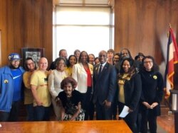 Tiana Caldwell (holding paper) and others with Mayor Quinton Lucas at the signing of Kansas City's Tenant Bill of Rights, December 2019. (Photo courtesy Tiana Caldwell)