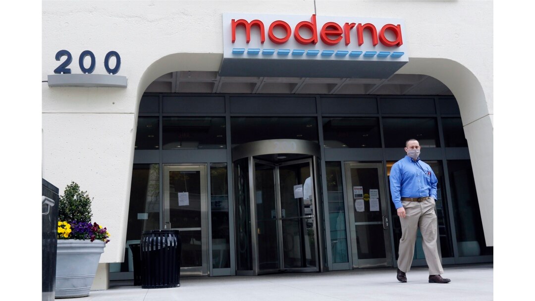 A man stands outside an entrance to a Moderna, Inc., building, Monday, May 18, 2020, in Cambridge, Mass. Moderna announced Monday that an experimental vaccine against the coronavirus showed encouraging results.