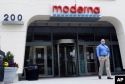 A man stands outside an entrance to a Moderna, Inc., building, Monday, May 18, 2020, in Cambridge, Mass. Moderna announced Monday that an experimental vaccine against the coronavirus showed encouraging results.