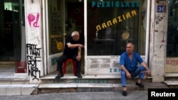 Men sit in front of a shop in central Athens, Greece, July 21, 2015. 