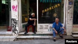 两名希腊人坐在雅典市中心的一个商店前 （2015年7月21日）