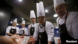 Lee Jin-soo (2nd R), 53, looks at a small octopus as he and others take part in Happy Guys Cooking Class in Seoul, South Korea, July 31, 2015. 