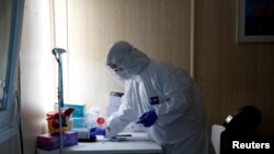 FILE - A healthcare worker works at a COVID-19 testing site as the spread of the coronavirus disease (COVID-19) continues in Budapest, Hungary, Oct. 27, 2020. 