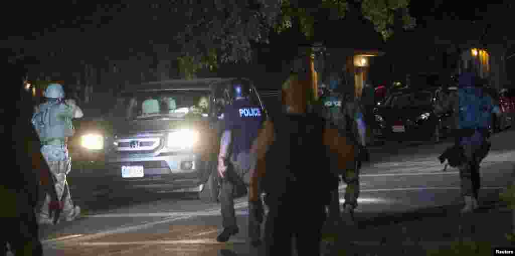 A polícia de choque pára um carro enquanto abre espaço entre os manifestantes, em Ferguson, Missouri, Ago. 13, 2014.