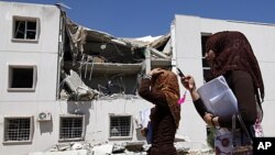 Students walk past a building at Fatih University, which was damaged during coalition air strikes the day before, according to Libyan officials, in Tripoli, June 18, 2011. Picture taken during guided government tour.