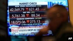 Financial news is displayed as people work on the floor at the New York Stock Exchange in New York, March 4, 2025. 