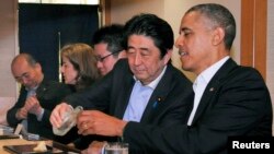 In this April 23, 2014 file photo, Japanese Prime Minister Shinzo Abe (2nd R) pours sake for U.S. President Barack Obama (R) as they have dinner at the Sukiyabashi Jiro sushi restaurant in Tokyo. (REUTERS/Cabinet Public Relations Office/Pool)