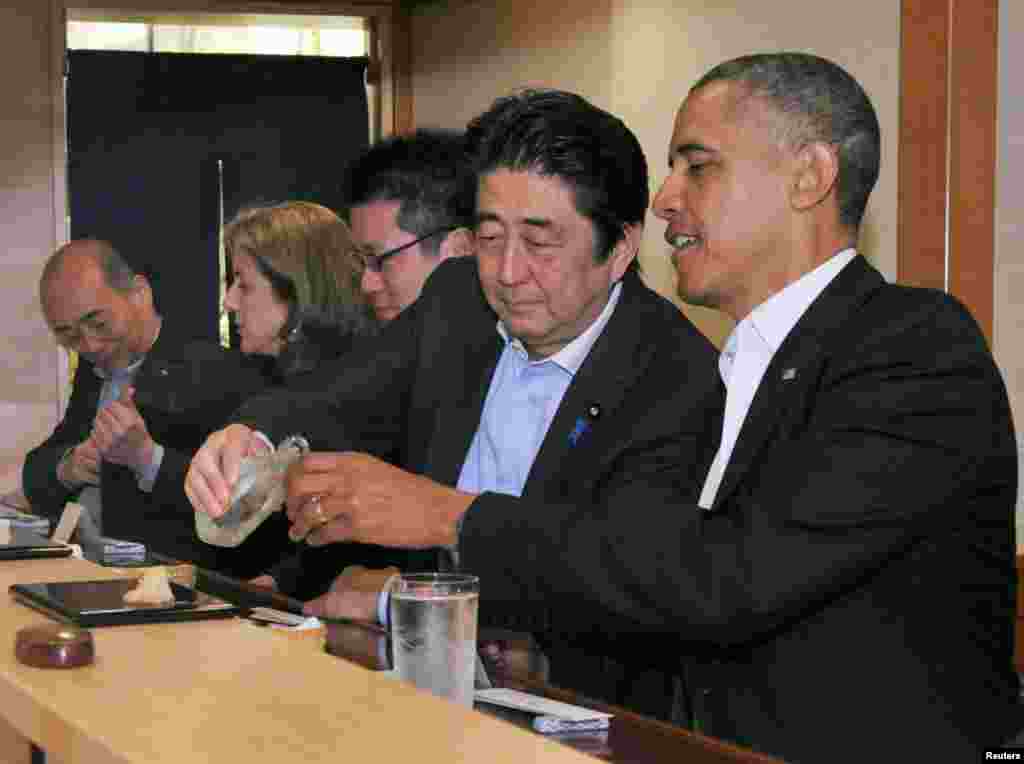 Japanese Prime Minister Shinzo Abe (2nd R) pours sake for U.S. President Barack Obama (R) as they have dinner at the Sukiyabashi Jiro sushi restaurant in Tokyo, in this picture taken April 23, 2014.