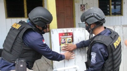 Petugas menempel poster memuat foto dan identitas empat teroris anggota MIT yang masih diburu dalam operasi Madago Raya. Sabtu (25/9/2021). (Foto: Courtesy/Humas Polda Sulteng)