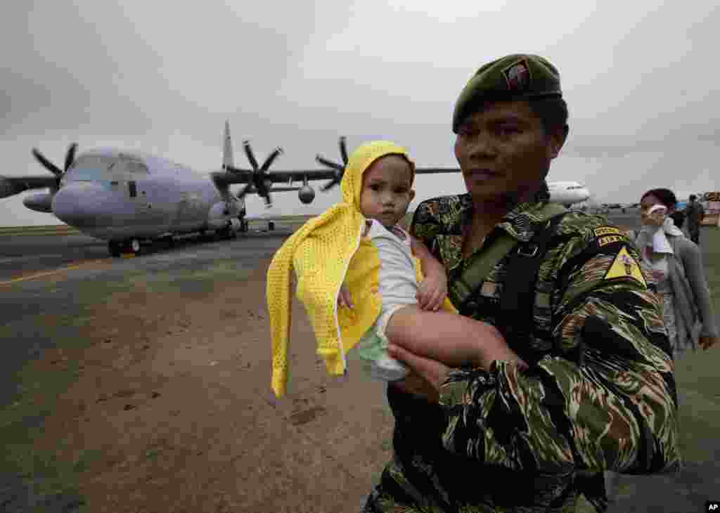 A soldier carries a baby to board a U.S. military transport plane at the damaged Tacloban airport, Tacloban city, Philippines, Nov. 17, 2013.
