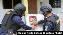 Petugas menempel poster yang memuat foto dan identitas empat teroris anggota MIT yang masih diburu dalam operasi Madago Raya. Sabtu (25/9/2021). (Foto: Courtesy/Humas Polda Sulteng)