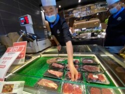 Seorang pekerja melabeli produk daging sapi yang sedang dijual di food court di Beijing, Jumat, 28 Agustus 2020.