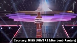 Ma Thuzar Wint Lwin, kontestan Miss Universe dari Myanmar, membawa poster bertuliskan "Pray for Myanmar" dalam peragaan busana tradisional di Hollywood, Florida, 13 Mei 2021. (Foto: Miss Universe via Reuters)