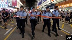 Police officers instruct street entertainers and spectators to leave on the last day before the Mong Kok's pedestrian zone closure in Hong Kong, July 29, 2018. 