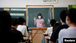 A student makes a presentation behind a plastic sheet to prevent the coronavirus disease infection during an english class at Takanedai Daisan elementary school in Funabashi, east of Tokyo, Japan July 16, 2020. (REUTERS/Kim Kyung-Hoon)