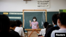 Tại một lớp học ở Nhật: Một sinh viên trình bày thuyết trình của mình sau tấm nhựa chắn nước bọt, Funabashi, Tokyo, tháng Bảy, 2020.