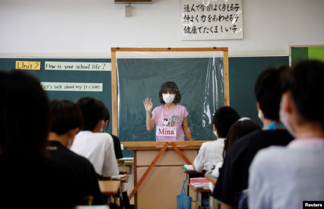 A student makes a presentation behind a plastic sheet to prevent the coronavirus disease infection during an english class at Takanedai Daisan elementary school in Funabashi, east of Tokyo, Japan July 16, 2020. (REUTERS/Kim Kyung-Hoon)