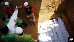 Muslims lower bodies of victims who were killed in the Saturday's landslide during a burial in Hulu Langat in central Selangor state, outside Kuala Lumpur, Malaysia, May 22, 2011