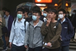 FILE - Youths wearing face masks to protect against the spread of the new coronavirus walk on a street in Taipei, Taiwan, March 30, 2020.